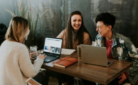 three-people-sitting-in-front-of-table-laughing-together.jpg three people sitting in front of table laughing together